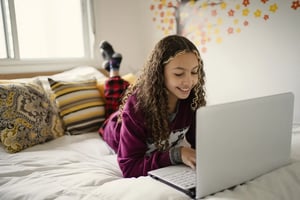 Student working from bed on laptop